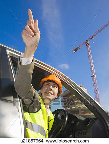 Picture - Woman pointing from car at building site. Fotosearch