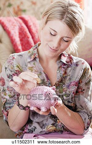 woman putting coin into piggy bank View Large Photo Image Stock Image - woman putting coin into piggy bank. Fotosearch