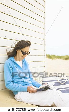 Woman reading against beach hut View Large Photo Image Stock Photograph - Woman reading against beach hut. Fotosearch