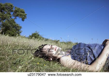 Stock Photo - Woman relaxing on hill. Fotosearch