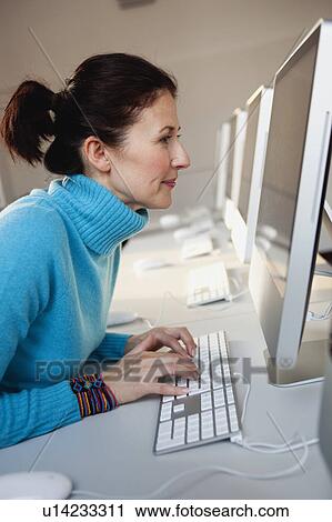 Stock Image - woman sitting at terminal typing. Fotosearch