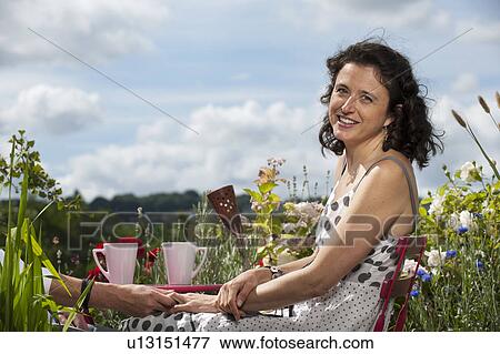 Stock Photo - woman sitting on balcony holding hand. Fotosearch