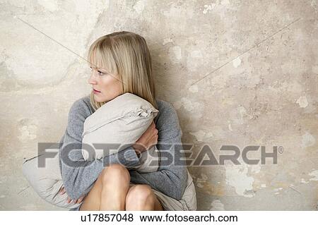 Stock Photo - woman sitting on floor with pillow. Fotosearch