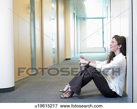 Stock Photo - Woman sitting on the floor, at work. Fotosearch