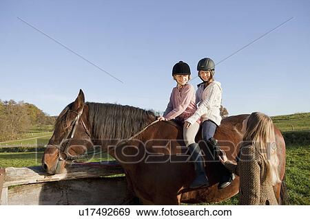 Stock Photo - Woman talking with two girls on a horse. Fotosearch