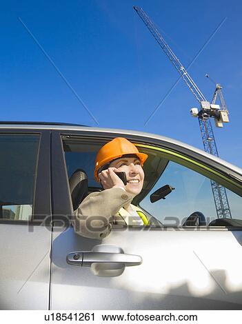 Stock Image - Woman Using Phone at building site. Fotosearch