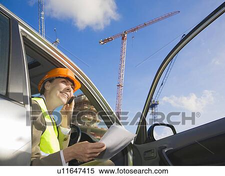 Stock Photography - Woman using phone at building site. Fotosearch