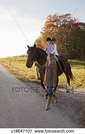 Woman walking a horse with two girls View Large Photo Image Stock Photo - Woman walking a horse with two girls. Fotosearch