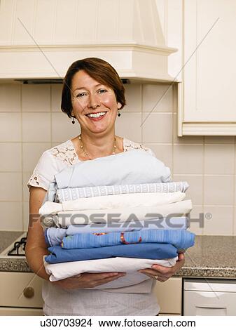 Woman with a pile of ironed washing View Large Photo Image Picture - Woman with a pile of ironed washing. Fotosearch