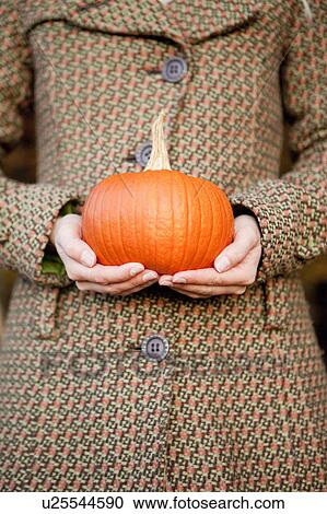 Stock Image - Woman with a pumpkin in her hands. Fotosearch