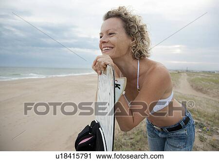 Stock Image - woman with kite board, overlooking beach. Fotosearch