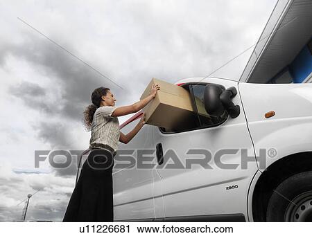 Stock Image - woman with large box and delivery van. Fotosearch