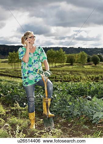 Stock Photograph - Woman with mobile phone in field. Fotosearch