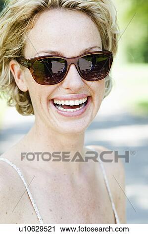 woman with sunglasses smiling at viewer View Large Photo Image Stock Image - woman with sunglasses smiling at viewer. Fotosearch
