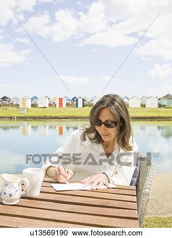 Woman writing at a table View Large Photo Image Stock Image - Woman writing at a table. Fotosearch