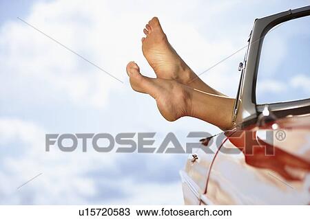 Stock Image - Woman's feet sticking out of car window. Fotosearch