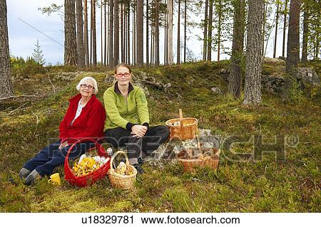 Stock Image - Women with mushroom baskets in forest. Fotosearch