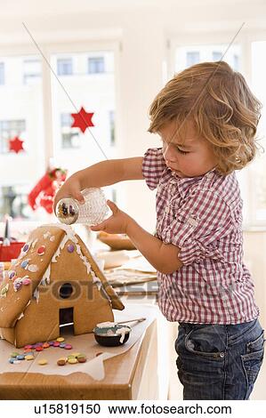 Stock Image - Young boy baking cake house. Fotosearch