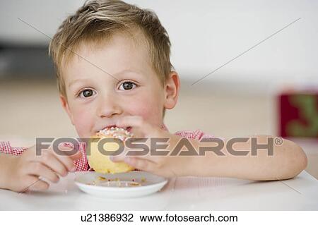 Stock Image - young boy eating sweet dumpling. Fotosearch