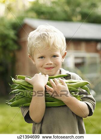 Stock Photo - young boy holding garden produce outside. Fotosearch