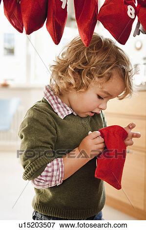 Stock Photo - Young boy inspecting a christmas sack. Fotosearch