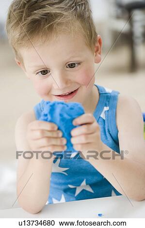 Stock Image - young boy playing with molding rubber. Fotosearch