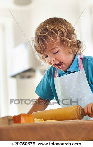 Stock Photography - Young boy rolling dough with rolling pin. Fotosearch