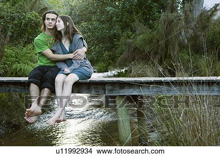 Young couple sitting on bridge View Large Photo Image Picture - Young couple sitting on bridge. Fotosearch