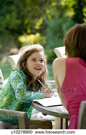 Stock Image - Young girl and mother chatting in garden. Fotosearch