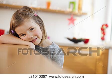 Stock Photo - young girl leaning on kitchen table. Fotosearch