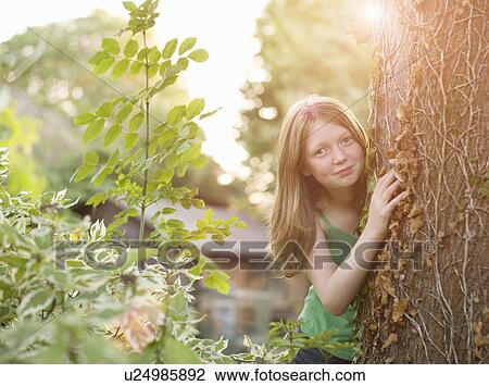 Young girl peeking from behind tree View Large Photo Image Stock Image - Young girl peeking from behind tree. Fotosearch