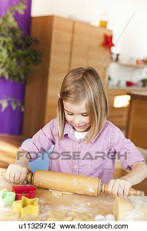 Stock Image - young girl rolling dough. Fotosearch