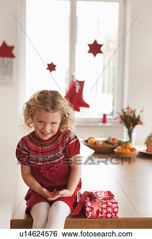 Stock Photograph - young girl sitting next to present. Fotosearch