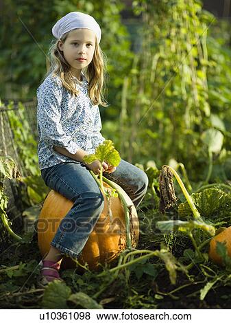 Young girl sitting on a pumpkin View Large Photo Image Stock Photo - Young girl sitting on a pumpkin. Fotosearch