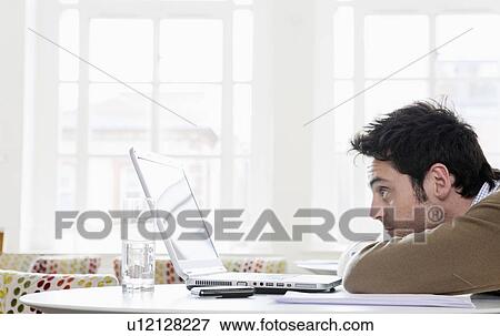Young man gazing into laptop View Large Photo Image Stock Photo - Young man gazing into laptop. Fotosearch