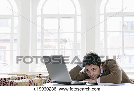 Stock Photograph - Young man gazing into laptop. Fotosearch
