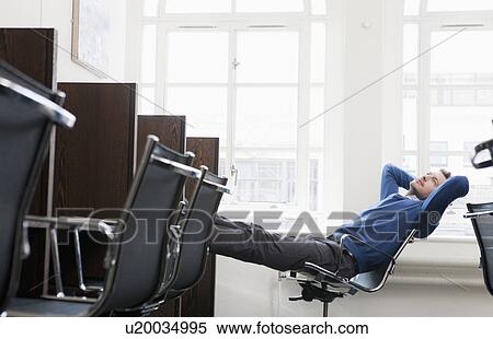Young man relaxing at a work station View Large Photo Image Stock Photography - Young man relaxing at a work station. Fotosearch