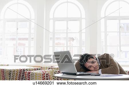 Young man resting on table, with laptop View Large Photo Image Stock Image - Young man resting on table, with laptop. Fotosearch