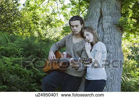 Stock Image - Young man with girl playing guitar. Fotosearch