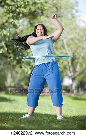 Stock Image - young plump girl doing hula hoop. Fotosearch