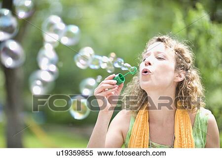 Stock Photography - young woman blowing bubbles. Fotosearch