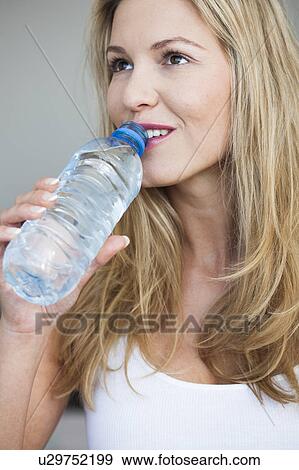 Young woman drinking bottle of water View Large Photo Image Stock Photo - Young woman drinking bottle of water. Fotosearch