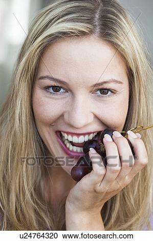 Stock Image - Young woman eating grapes. Fotosearch