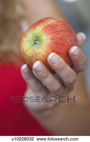 Young woman holding an apple View Large Photo Image Stock Image - Young woman holding an apple. Fotosearch