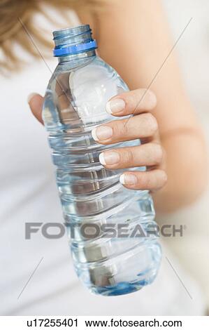 Stock Image - Young woman holding bottle of water. Fotosearch