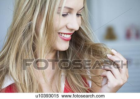 Stock Photography - Young woman holding her hair smiling. Fotosearch