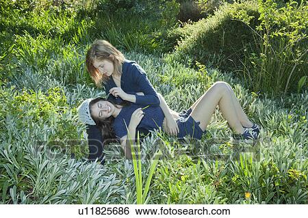 Stock Photograph - Young woman tickling girl with leaf. Fotosearch