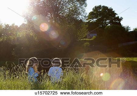 Stock Photography - 2 young kids sitting in long grass.. Fotosearch