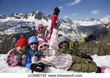 Stock Image - 5 kids lying in the snow.. Fotosearch