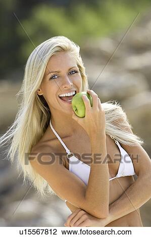 Stock Image - A blond beach girl with an apple. Fotosearch
